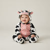 Twinkles baby polar fleece cow costume jumpsuit with hood, featuring black and white spots and pink accents.